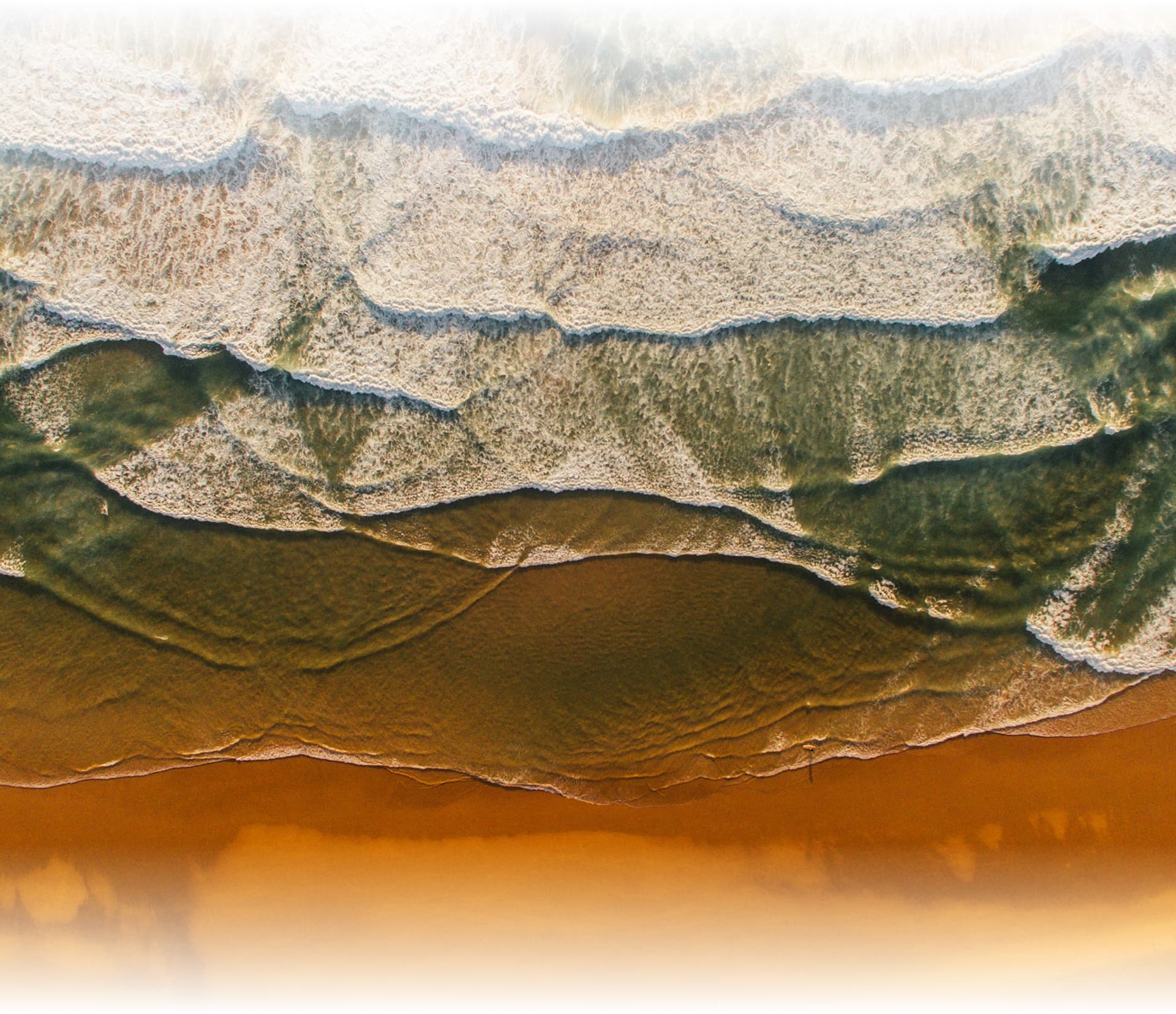 Aerial view of ocean waves meeting sandy beach